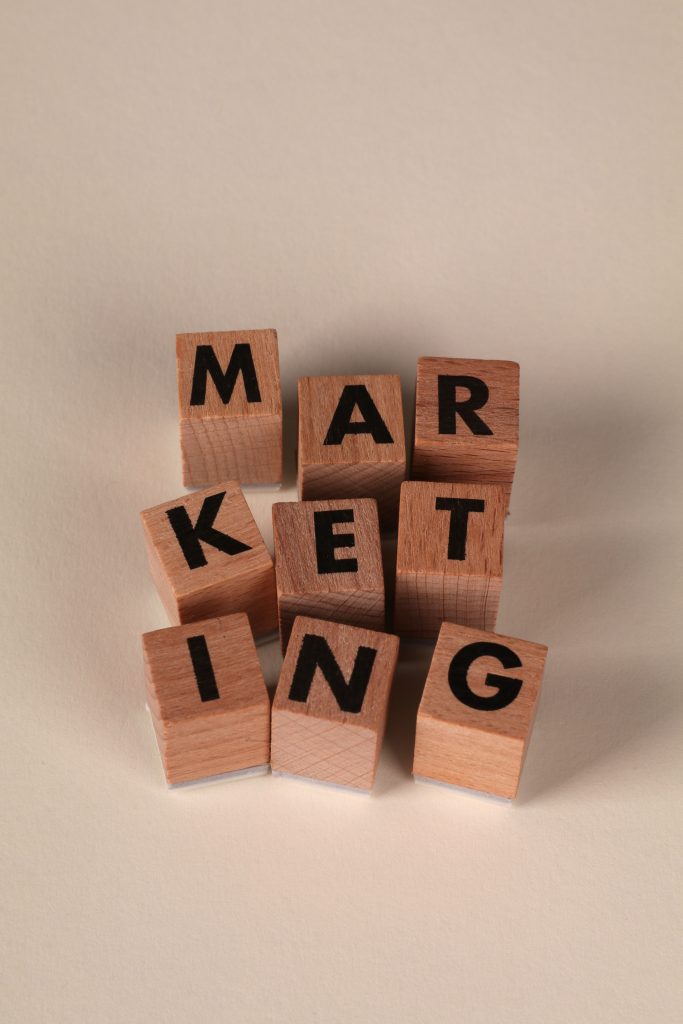 Wooden blocks arranged to spell 'MARKETING' on a neutral background.